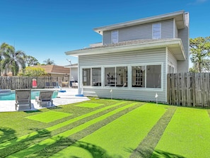 A two-story house with a swimming pool, a fenced backyard, and a well-maintained lawn.