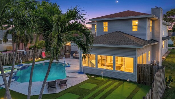 A two-story house with a swimming pool, a fenced backyard, and a wooden deck. - WhiteIris-5-Bedroom Home with Pool, Mini Golf, & Heated Jacuzzi in Boynton Beach (Boynton Beach)
