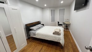 A bedroom with a bed, a desk, and a wardrobe.