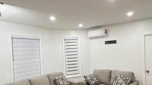 A living room with two grey sofas, wooden flooring, white walls, and recessed ceiling lights.