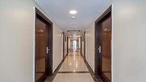 A long, well-lit hallway with wooden doors on either side, leading to a bright exit at the end. - Treebo D Consulate Hitech City (Hyderabad)