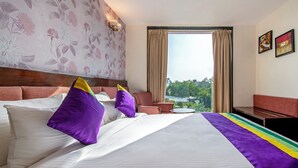 A hotel room with a large bed, a view of the outdoors, a small table, and a sofa. - Treebo D Consulate Hitech City (Hyderabad)