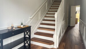 Un escalier avec des marches en bois et une rampe blanche, menant à une porte au fond.