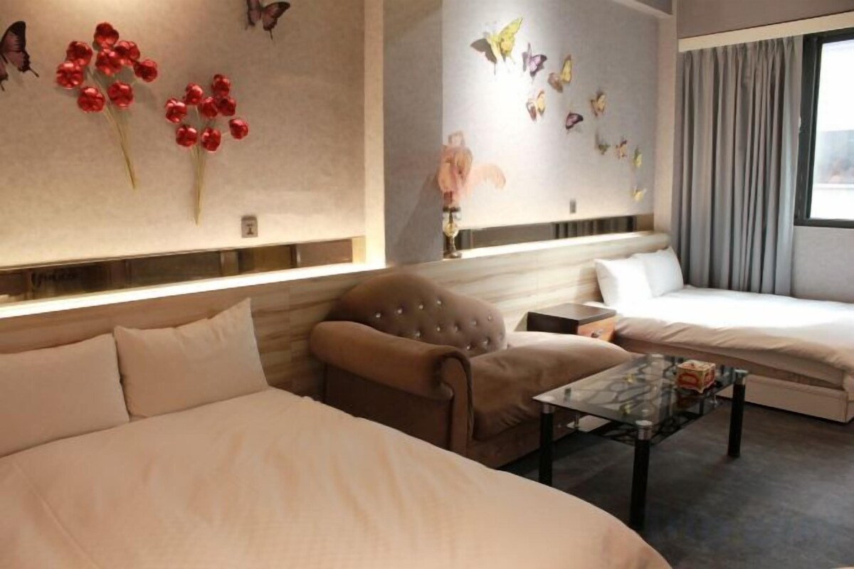 Una habitación de hotel con una cama grande, un sofá más pequeño, una mesita de café y decoración mural.