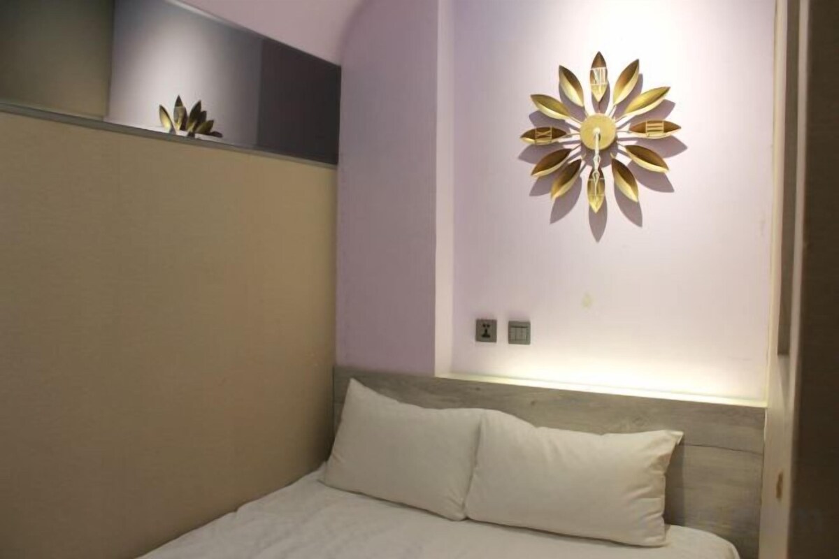 Une chambre à coucher comprenant un lit, un luminaire fixé au mur et un élément décoratif mural.