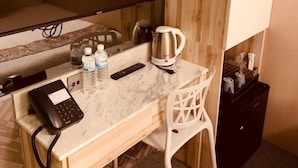 A small hotel room with a wooden desk, a chair, a television, a coffee maker, and a telephone. - Artinn Kaifeng hotel (Taipei)