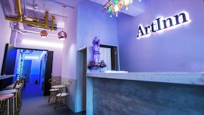 A reception area with a counter, chairs, and a wall sign that reads "ArtInn". - Artinn Kaifeng hotel (Taipei)