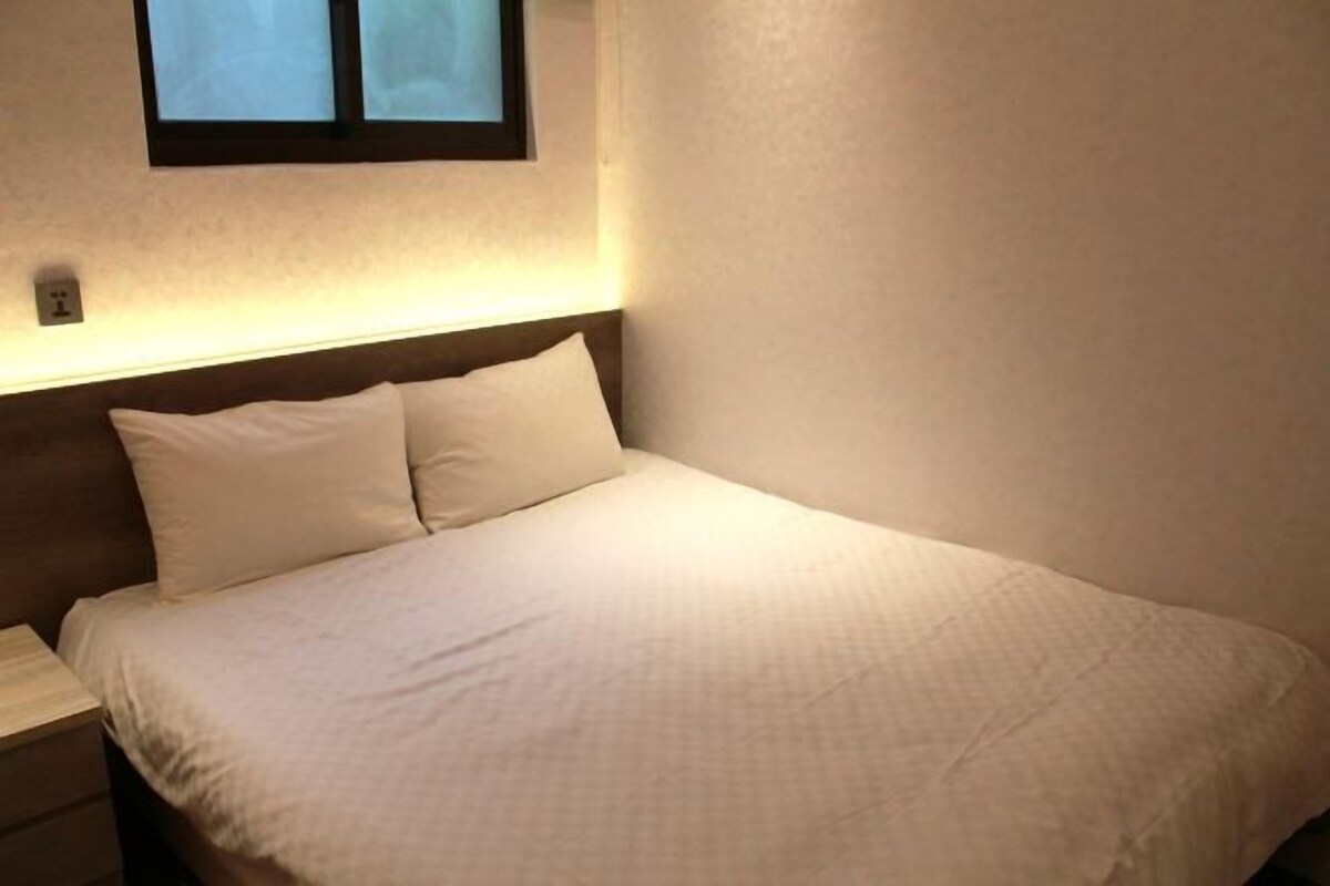 Un lit bien fait, avec du linge de lit blanc, dans une pièce au design simple et épuré.