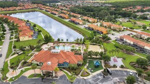 A residential area with a large swimming pool, houses with red roofs, and a central park area.