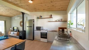 Una cocina moderna con un refrigerador de acero inoxidable, microondas, horno y una mesa de comedor de madera.