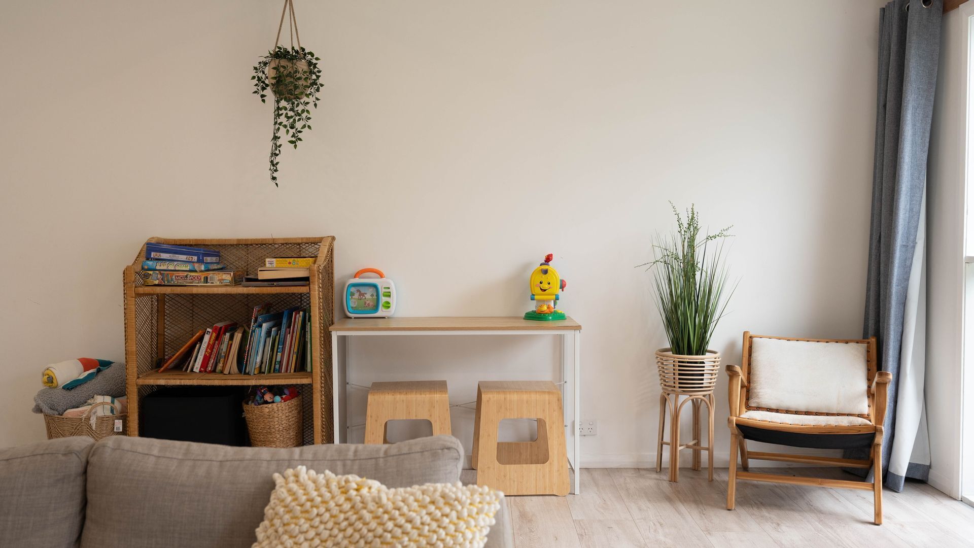A cozy living room with a bookshelf, a small table, a chair, and a hanging plant.