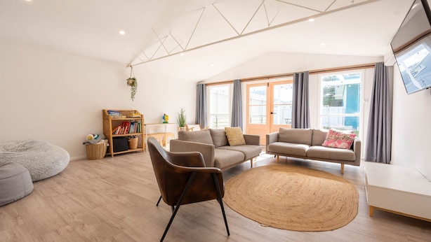 Una sala moderna con sofá, sillón y una alfombra grande.