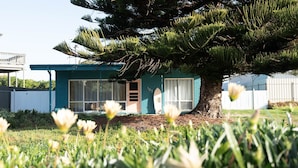 Una casa con un árbol grande al frente, una ventana con cortinas y el número 185 en la pared.