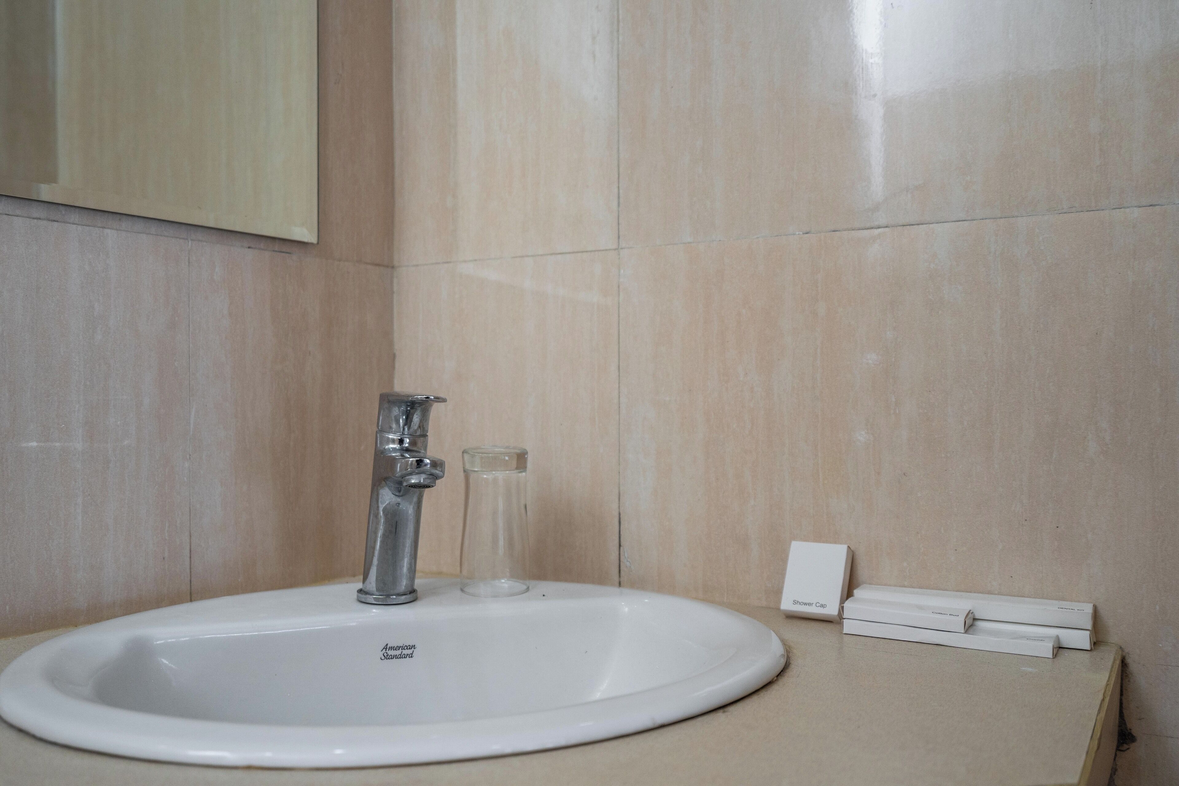 Un baño con un lavamanos blanco, un espejo y una cofia sobre la encimera.