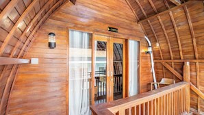 Una cabaña de madera con un balcón, un letrero que dice "Bungalow 2" y una escalera que conduce al piso superior.