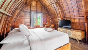 Un dormitorio acogedor con paneles de madera, una cama, un televisor y un escritorio.