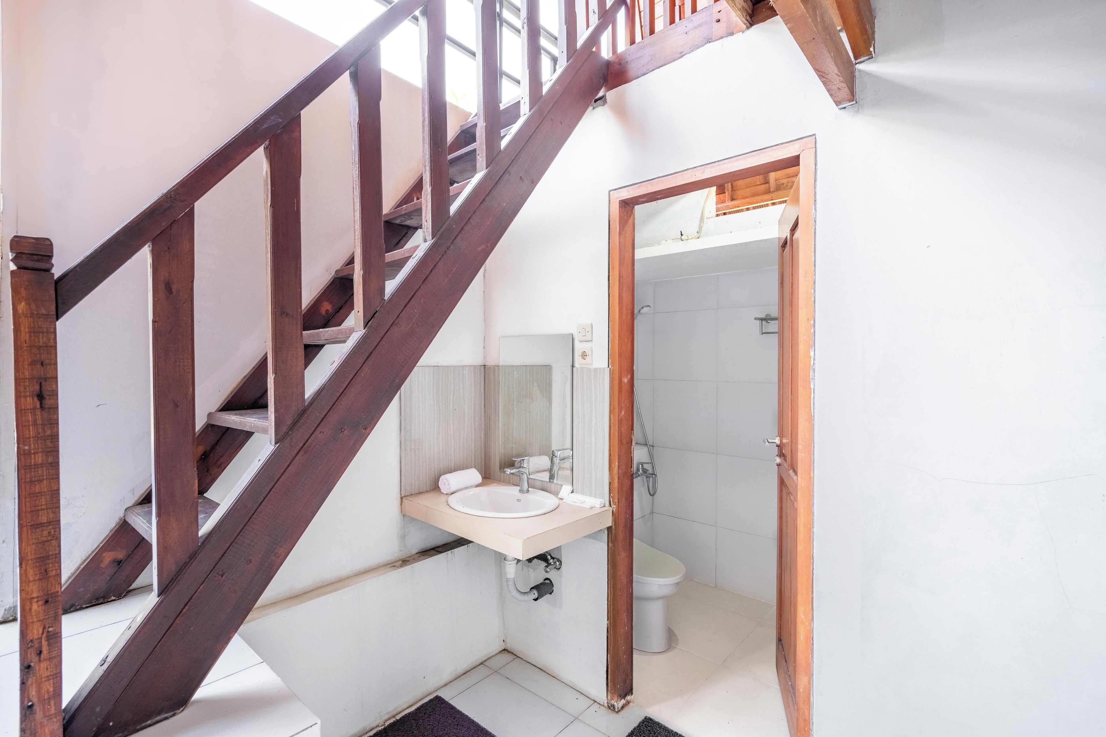 A bathroom with a wooden staircase, a sink, and a toilet.