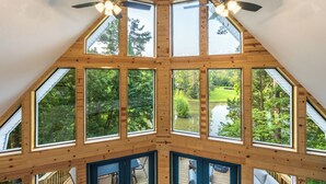 A cabin with a sloped roof, multiple skylights, and a view of a lake surrounded by trees.