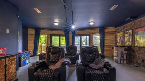 A room with three massage chairs, a wooden cabinet with artwork, and a wall with posters.
