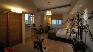 Una habitación de hotel moderna con una cama, un escritorio, una silla y una planta grande.
