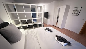 Un dormitorio moderno con una cama, un televisor, un armario y un cuadro en la pared.