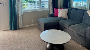 Ein Wohnzimmer mit grauem Sofa, einem runden Couchtisch und einem Deckenventilator.