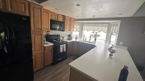 Una cocina moderna con armarios de madera, un refrigerador negro, un microondas y una estufa.