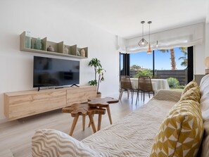 Relax in this stylish living room with a flat-screen TV, comfortable sofa, and dining area.