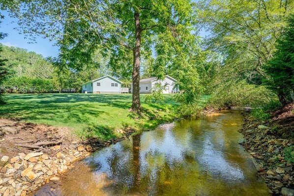 Une maison avec une cour verdoyante et un ruisseau.