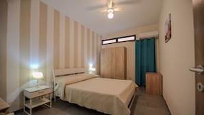 A bedroom with a bed, nightstands, a wardrobe, and a ceiling fan.