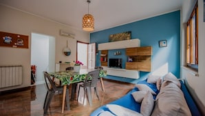 A modern living room with a blue accent wall, a dining area with a table and chairs, and a cozy seating area with a sofa.