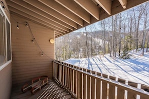 A wooden balcony with a railing, a clock, and a sled.