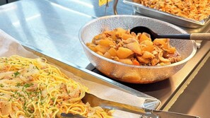 Buffetpöydässä on pastaa ja erilaista ruokaa tarjolla.