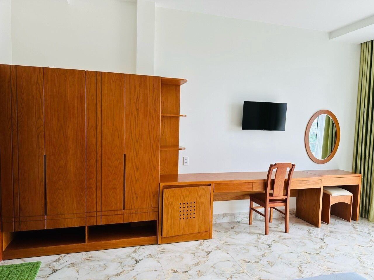 A room with a wooden desk, a chair, a television, and a wardrobe.