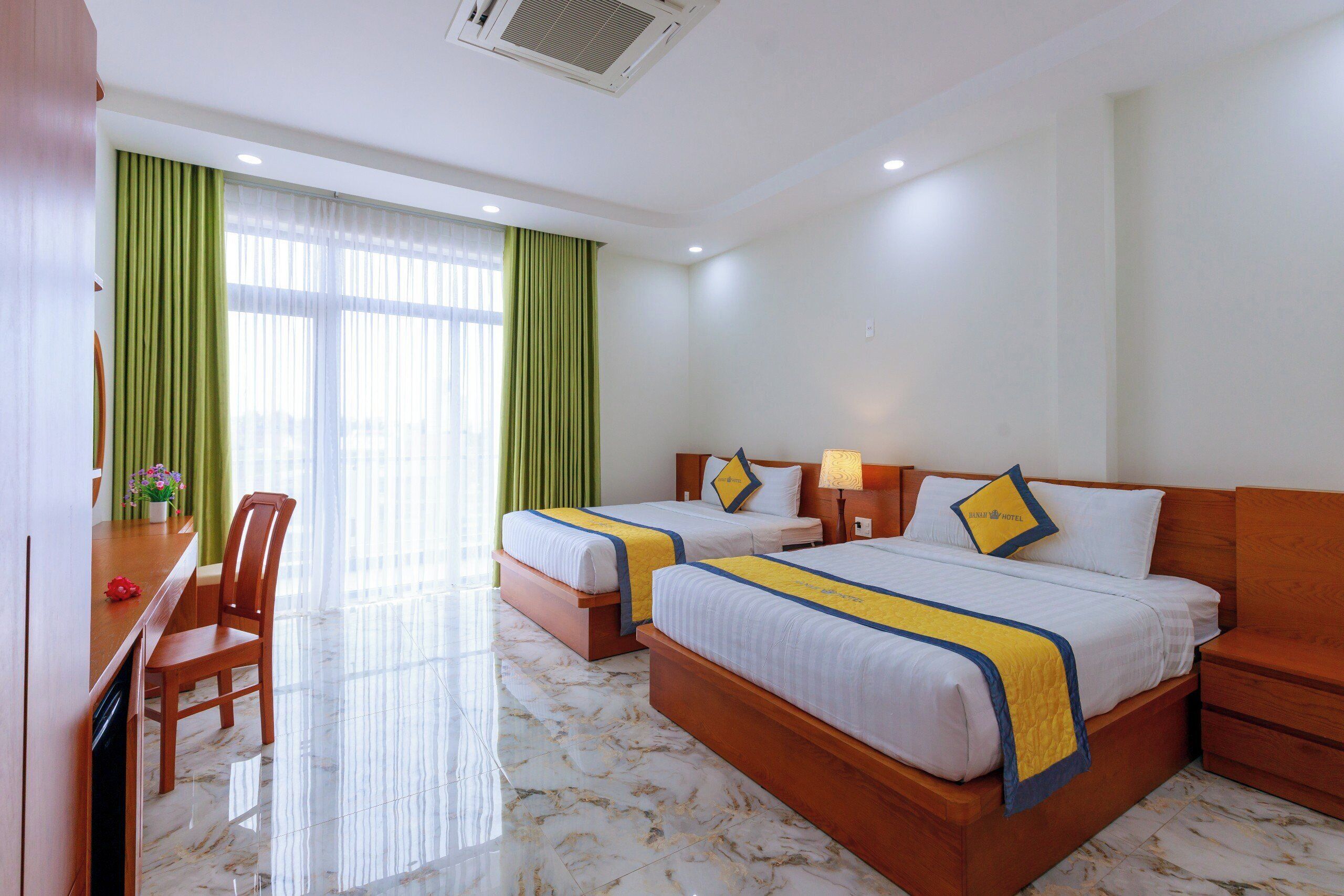 A hotel room with two beds, a desk, and a chair.