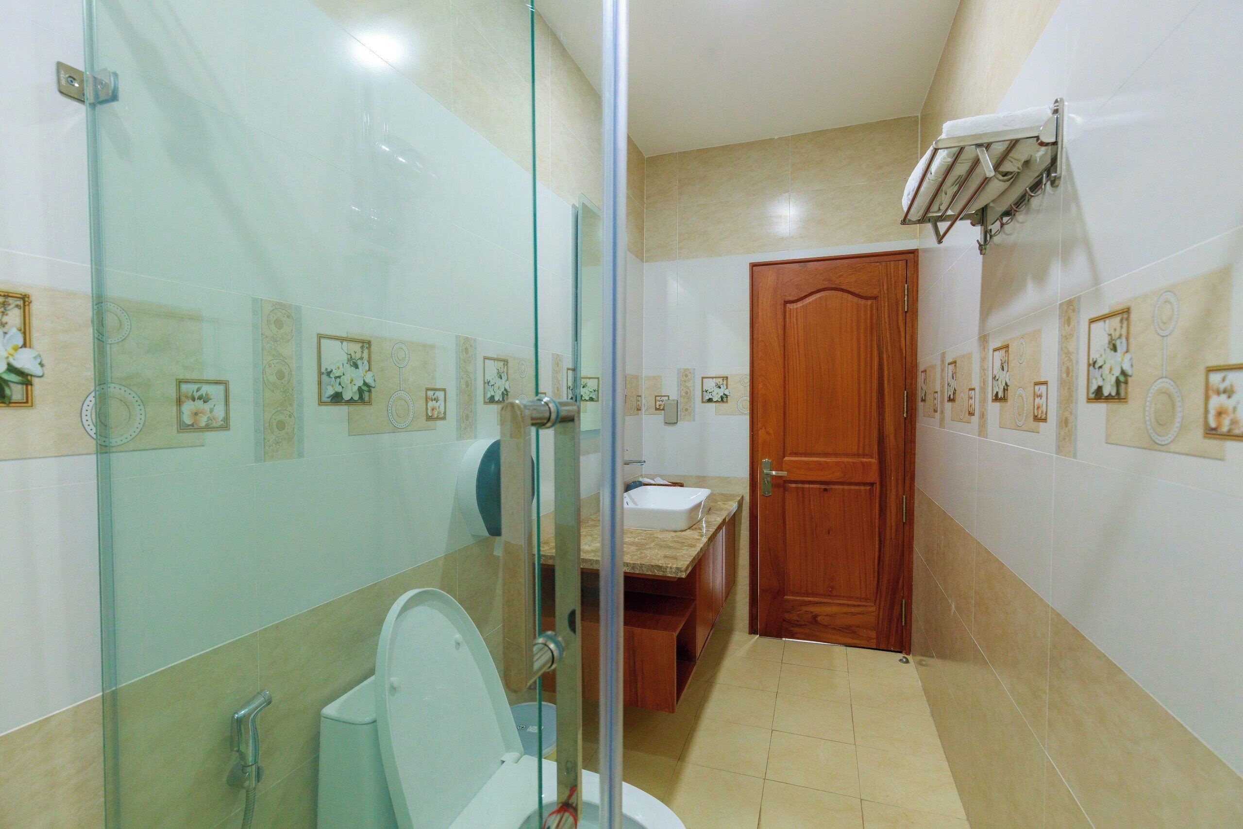 A bathroom with a glass-enclosed shower, a toilet, a sink, and a wooden door.