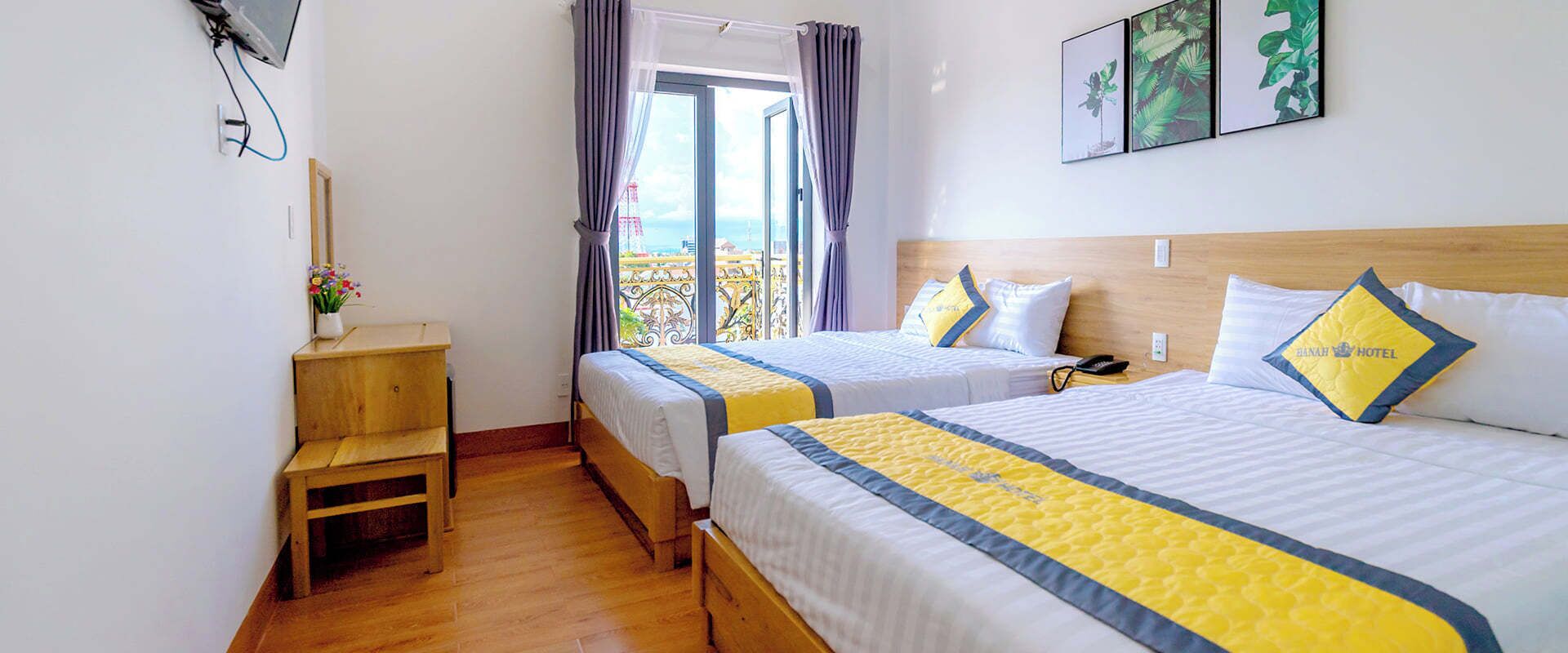 Una habitación de hotel con dos camas, una mesita de noche de madera, un teléfono y una ventana con cortinas.