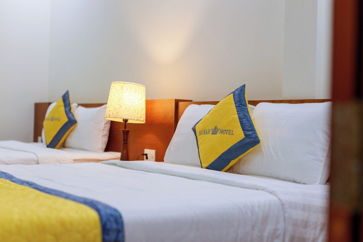 Una habitación de hotel con dos camas, cada una con un cojín que muestra el logotipo del hotel.