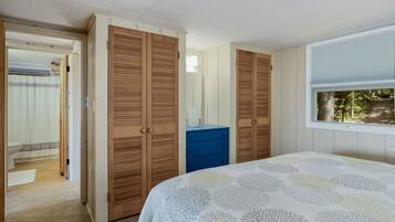 Ein Schlafzimmer mit zwei Holzschränken, einer blauen Kommode und einem Bett mit einem gemusterten Bettbezug.