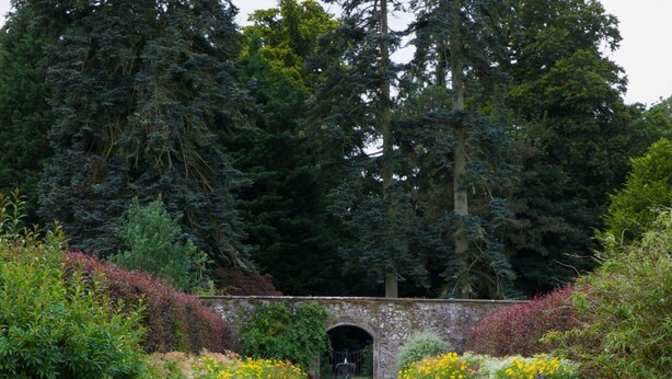 A stone urn in a garden with a pathway leading to a stone archway. - Stables Cottage, Kailzie - sleeping 2 guests in one bedroom (Peebles)