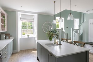 A kitchen with a central island, white cabinets, and a window with a view of greenery.