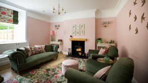 A cozy living room with a fireplace, green sofas, and a floral rug. - Stables Cottage, Kailzie - sleeping 2 guests in one bedroom (Peebles)