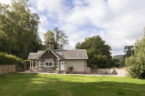 A stone house with a sloped roof, a front door, and a small porch. - Honeysuckle Cottage - sleeping 4 guests in 2 bedrooms (Peebles)