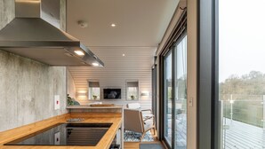 Una cocina moderna con encimera de madera, estufa integrada y un amplio ventanal con vistas a una terraza.
