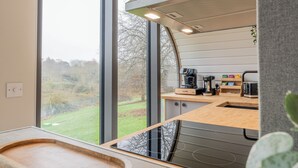 Una cocina moderna con un gran ventanal, una cafetera y una encimera de madera.