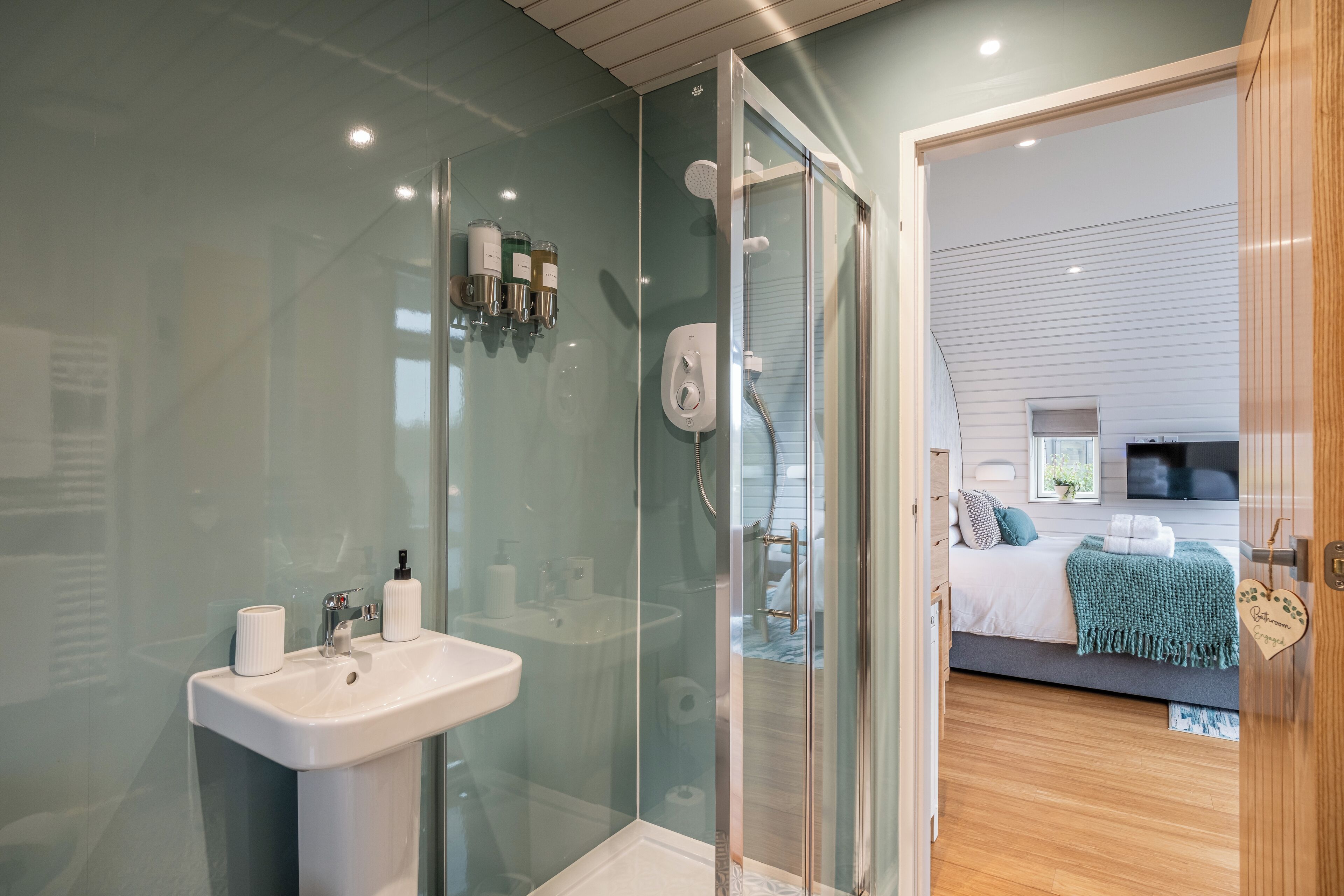 A modern bathroom with a glass shower enclosure, a white sink, and toiletries.