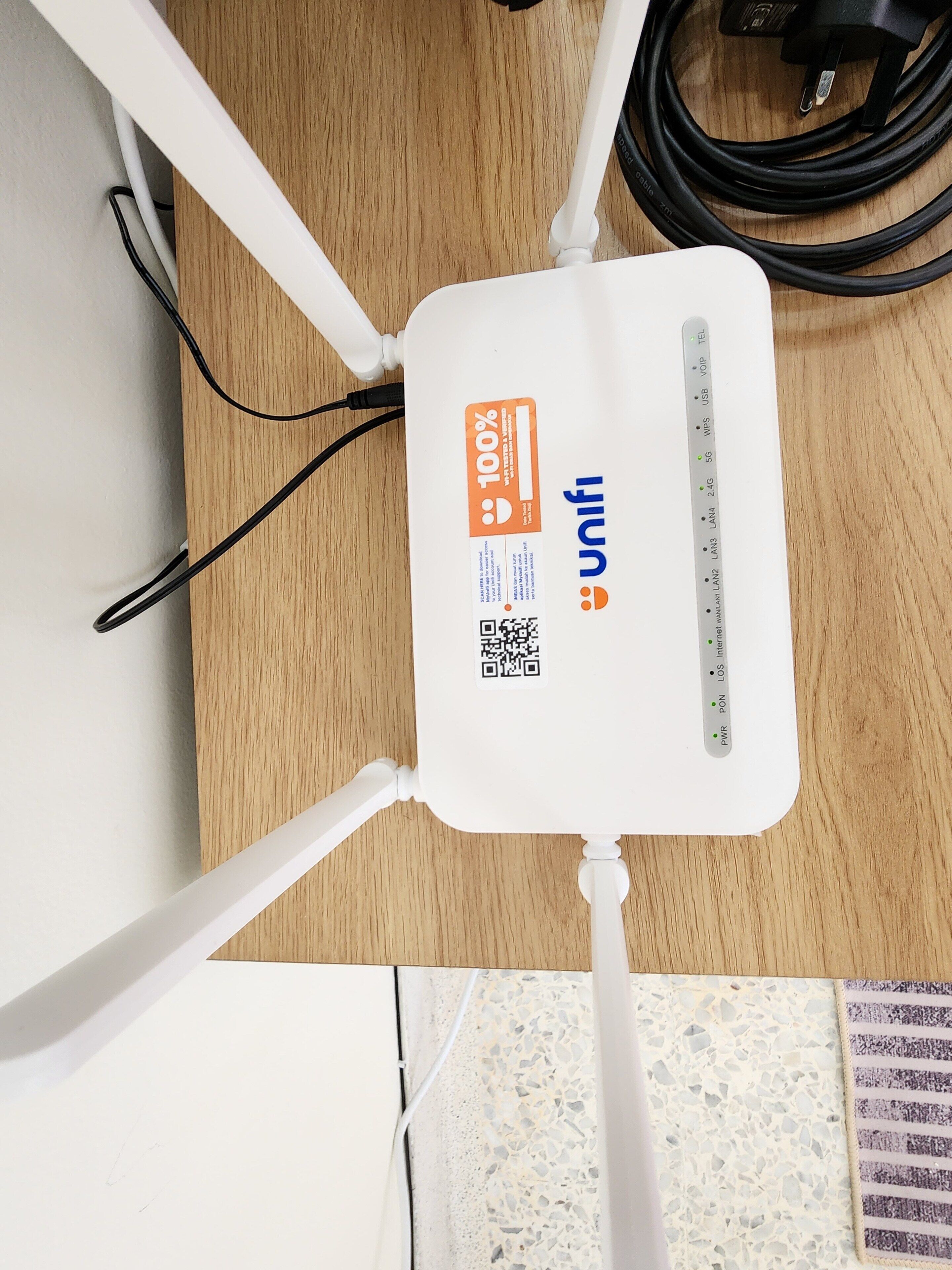 A white Wi-Fi router with a label indicating 100% speed and the brand 'unifi'.