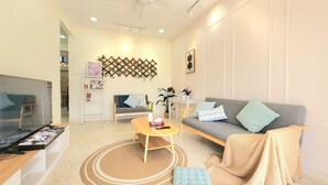 Un salon avec un canapé gris, une table basse, un téléviseur et un mur décoratif.