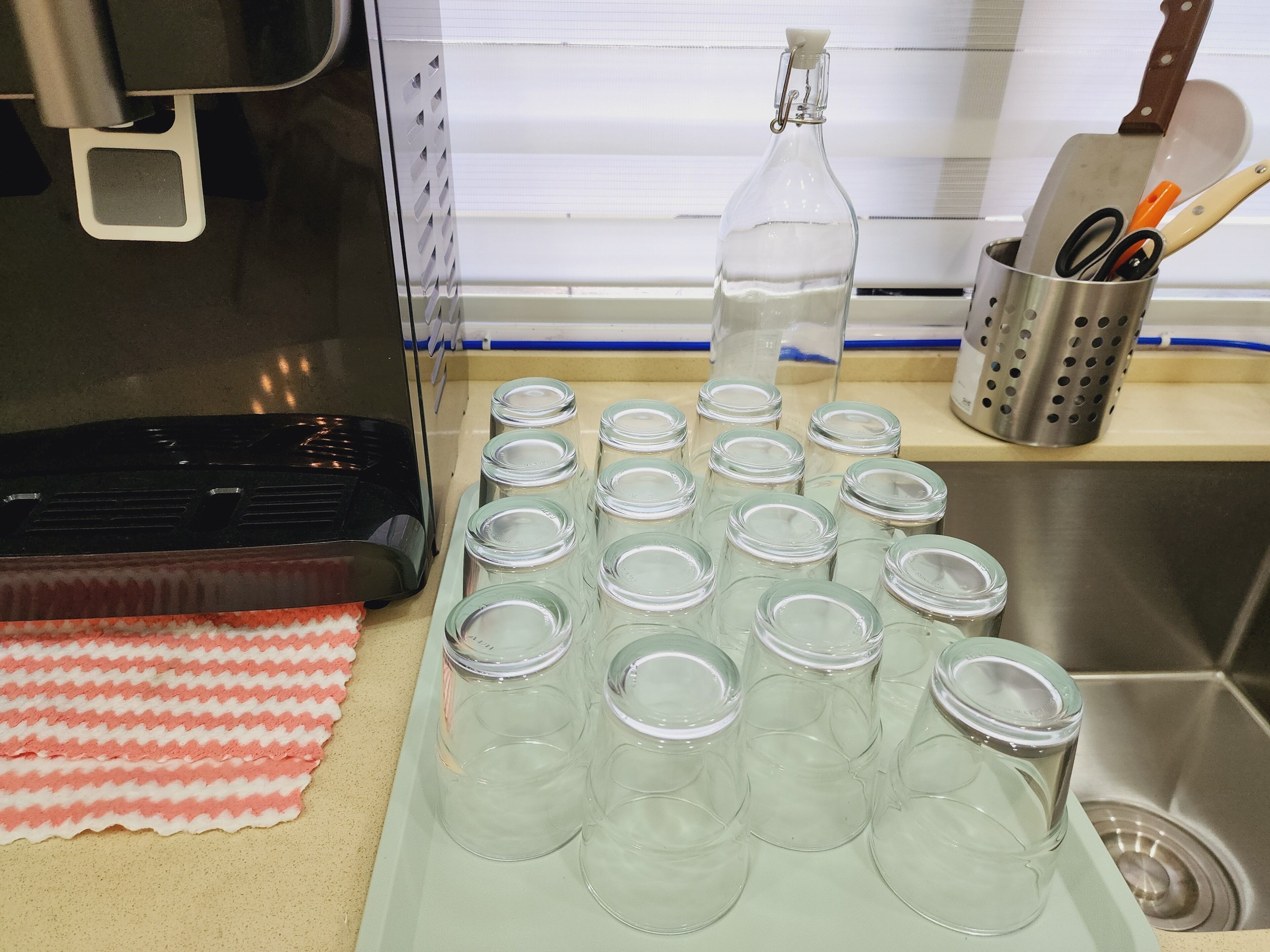 A kitchen counter with a coffee maker, a bottle of water, and several empty glass jars.
