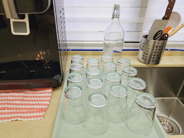 Una encimera de cocina con una cafetera, una botella de agua y varios frascos de vidrio vacíos.